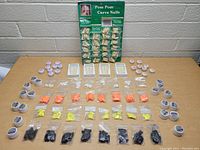 Full overview of the lot showing the green display card with Pom Pom Curve Nails, small jars of acrylic powder labeled Pom Pom, and multiple small sealed bags of acrylic powder or tips in various colors arranged on a table.