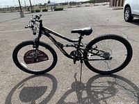 Side view of black Mongoose Stand Off mountain bike with 26 inch wheels, aluminum frame, visible suspension, kickstand down.