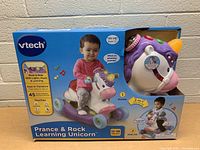 Front-facing box including image of toddler using the toy and toy partially visible in window on the right side.