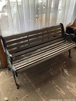 Full side view of antique garden bench showing wooden slats and cast iron end supports