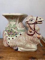 Side view of ceramic camel side table showing sculpted details and painted decorations