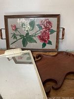 Three vintage trays displayed: floral wooden tray, curved wooden tray, and mirrored tray.