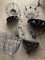 Overview of metal garden decor items showing various shaped wall planters and baskets with different ornate metalwork designs.