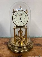 Full view of the vintage Kundo anniversary clock showing gold-tone base and glass dome enclosure.