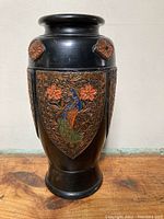 Full view of vintage Japan vase showing black body with embossed peacock and flower panels and floral details near the neck.