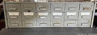 Front view showing all 24 metal drawers arranged in three rows with pull handles and some label holders.