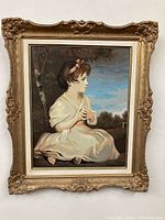 Frontal photo of the framed paint by number showing the full artwork of a seated young girl and ornate detailing on the frame.