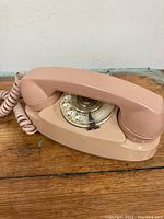 Front view of the beige vintage Princess rotary dial telephone on a wooden surface.