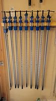 Nine aluminum bar clamps hanging on a wall