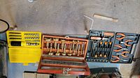 Wood bits, ratchet screwdriver with bits and sockets, and pliers set in their cases on floor.