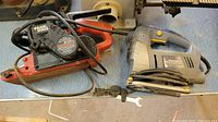 Side view of Black & Decker Dragster belt sander and Mastercraft serpentine saw on a work surface with cords coiled, showing general appearance and condition.