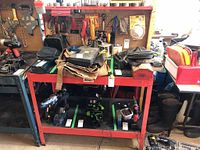 Front view of the Jobmate metal work bench showing the two-tone red structure and partial contents on both shelves.