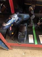 Two cordless drills, one dust buster, and one charger on a shelf