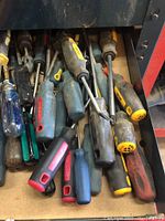 Drawer filled with assorted screwdrivers of different sizes and handle types