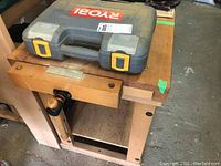 Top of bench showing work surface, front vise and a Ryobi case placed on top