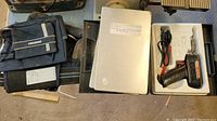 Wide view showing Mastercraft tool belt, wood drill bits, scissors, pliers, and white box for soldering kit arranged on floor