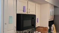 Kitchen cabinets shown with a microwave and items stored inside cabinets as indicated with notes on the cabinet doors