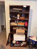Front view of the bookcase filled with various items showing the overall condition and shelving structure.