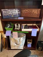 Shelves showing two wooden running themed medal holders, shelving with small boxes and accessories, and large tote bag below
