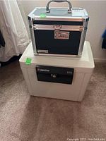 Photo showing side view of the black and silver Vaultz combination lock box on top of the Sentry 1170 safe.