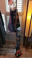 Photo of three Sparkle Skirts running skirts on white hangers on a metal rack, with a rolled blue fitness mat next to them and a pair of red and black hand weights on the floor below. Nearby floor lamp and window with shutters visible. Seller notes rack and lamp not included.