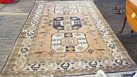 Full view of the 7x10 feet Oriental style area rug with geometric medallions and symbolic patterns on beige background.
