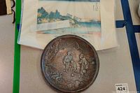 Photo of the set showing both the Asian watercolor painting and the round metal wall plaque with figures in relief.