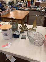 View of all items including brass sailboats, crystal bowl, ceramic jars on a white table