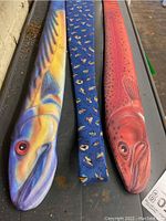 Three fish-themed ties displayed lying flat: two large fish-shaped ties, one blue and yellow fish and one red fish, and one blue tie with multiple fish pattern.