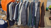 Men's clothing hung on a rack showing multiple jackets, coats, and suits in various colors including dark blue, brown, and black.