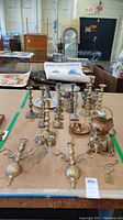 Wide view of 25 metal items including candlestick holders, cat figure, dishes