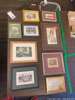 Ten framed travel destination prints and illustrations arranged on table, varying frame styles and colors