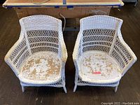 Top view of two matching white wicker chairs showing wear on seat painting.