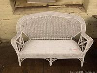 Front view of white wicker loveseat showing full seating area, backrest, and armrests.