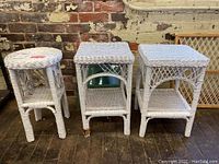 Photo of 3 white wicker side tables, two square topped with lattice weave and one round topped with decorative scrollwork sides.