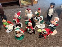 Grouped shot of nine Annalee Dolls and one Byers Choice caroler, arranged on carpeted floor showing scale and variety