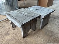 Two antique wooden stools showing peeling paint and worn condition, placed on a wooden floor.