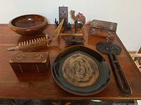 Overview showing all items: wooden serving bowl, miniature carved boat with figures, wooden box, coaster set, match holder, tray, Dutch shoe ashtray, and camel figurine.