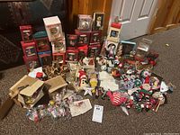 Photo showing a large assortment of boxed and loose Christmas ornaments and vintage-style wooden figures spread on carpet.