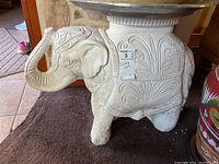 Side view of white elephant stand showing detailed carved patterns, raised trunk, and overall shape.