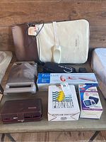 View of all items in the lot including heating pad, Prozone light therapy device, Omron blood pressure monitor, various handheld massagers, and device cases.