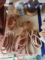 Photo showing two pottery wind chimes with oval-shaped pottery rings in terracotta and beige tones hanging beneath two pottery bells on a table surface.