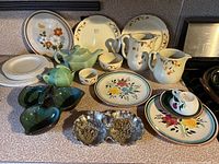 Full lot of dishware showing variety of plates, cups, saucers, pitchers, teapot, creamer, and divided dish.