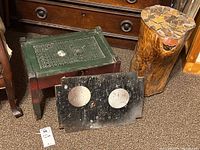 Photo showing the vintage wooden stool with a woven top, the black removable wooden cover with two circular cutouts placed in front, and the natural log side table with a mosaic stone top.