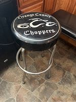 Front angle view of Orange County Choppers bar stool seat and metal legs on tiled floor.