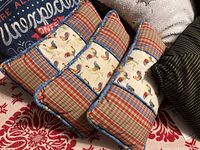 Three rooster and plaid patchwork throw pillows stacked together showing patch design and blue rickrack trim.