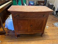 Front view of vintage wooden cabinet showing one drawer and two doors below, wood veneer heavily peeling and visible scratches.