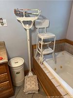 Full view of vintage Fairbanks scale, metal Dover diaper pail, and foldable metal step stool near bathtub.