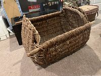 Side angle view of the woven basket showing wooden rail handles and coarse weave.