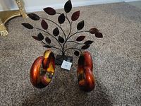 Two ceramic decorative coil items and one aluminium decorative leaf tree on gray carpet.